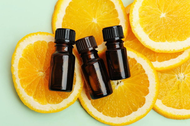 Essentiële olie in donkere glazen flessen op verse plakjes sinaasappel. Cosmetisch, gezond concept. Bovenaanzicht - Foto, afbeelding