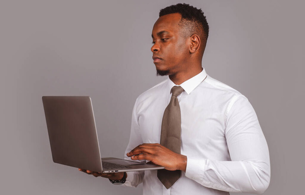 Jovem empresário usando laptop e tomar notas no worklace no escritório moderno, espaço livre - Foto, Imagem