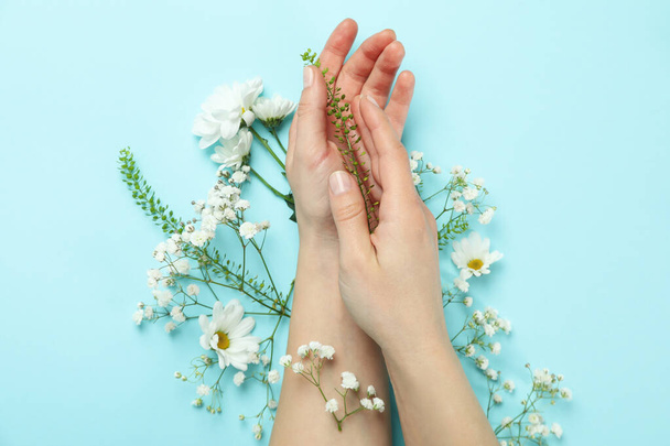 Female hands with flowers on blue background - Foto, Bild