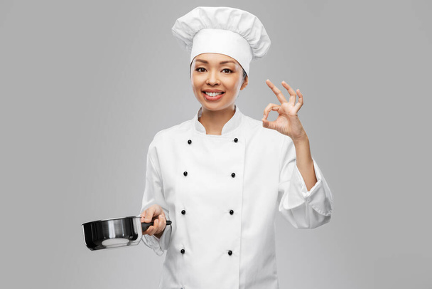 happy female chef with saucepan showing ok gesture - Fotó, kép