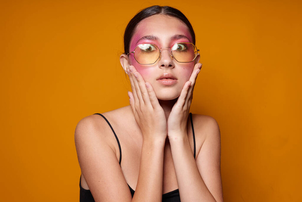 Portrait of beautiful young woman fashion glasses pink face makeup posing attractive look yellow background unaltered - Fotoğraf, Görsel