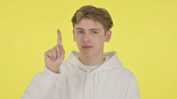Young Man showing No Sign by Finger on Yellow Background - Photo, Image