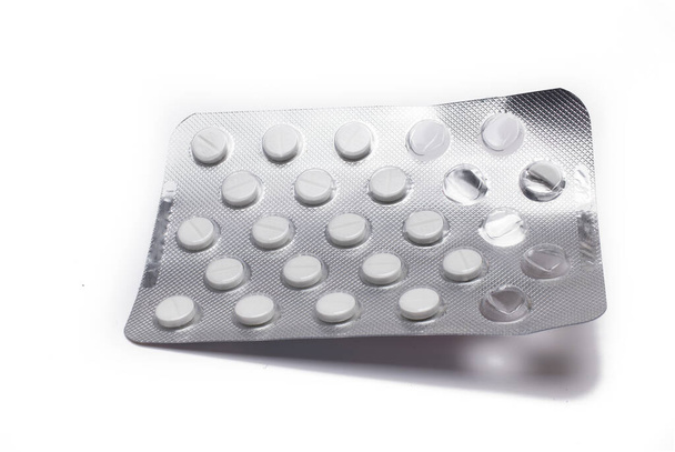 Close up of silver blister with small white film tablets on white background tablets in package medicine - Valokuva, kuva
