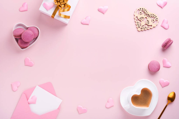 Valentines Day card. Pink empty envelope, macaron macaroon cookie and heart shaped coffee cup on pink background. 8 March, Womens Mothers Valentines Day, Birthday. Flat lay, top view, copy space. - Photo, image
