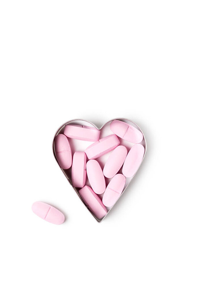 Pink organic vitamin tablets in heart-shaped form on white background, healthy lifestyle concept - Foto, immagini