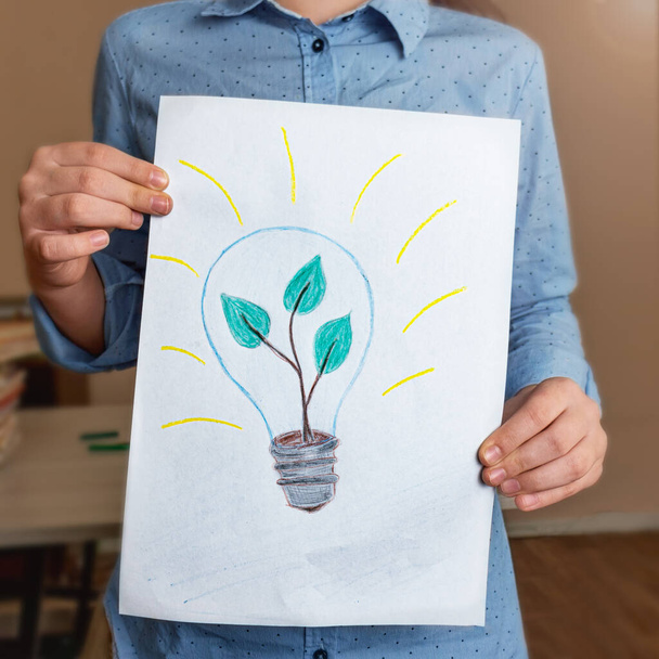 Child's drawing of a light bulb with a green plant inside. Ecology conservation concept. concept of an initiative and a new idea.Green plant conservation concept. Solar households and ecological energy - Foto, afbeelding