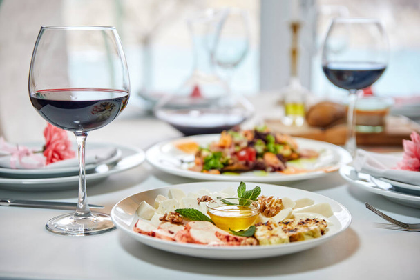 Gasten kunnen gebruik maken van een eettafel met een glas rode wijn en een voorgerecht. Close-up, selectieve focus - Foto, afbeelding