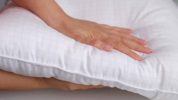 Młoda kobieta dotykająca miękkiej białej poduszki, zbliżenie. jak wybrać poduszkę, sztuczne wypełnienie - Materiał filmowy, wideo