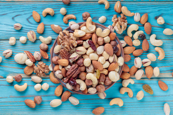 Nueces mezcladas en un plato sobre una mesa de madera. Nueces, pistachos, almendras, avellanas y anacardos. - Foto, Imagen