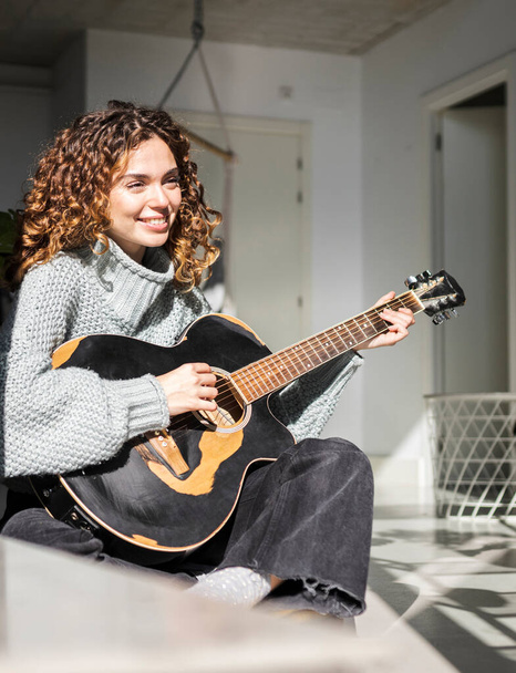 pretty hispanic curly hair woman playing guitar at home - Photo, Image