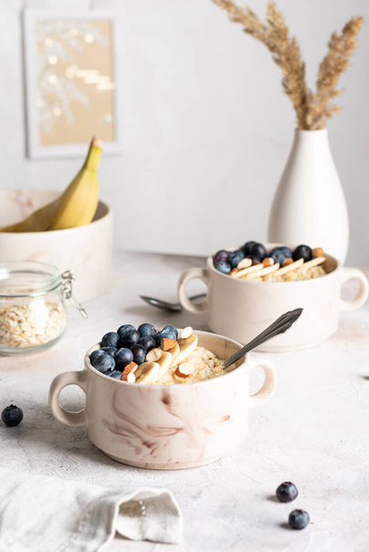 Close up of bowls with oatmeal porridge with blueberries for breakfast - Φωτογραφία, εικόνα