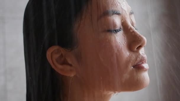 Κινέζα νεαρή κυρία που κάνει ντους κλειστά μάτια στο εσωτερικό μπάνιο - Πλάνα, βίντεο