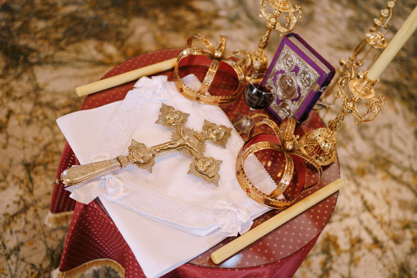 Крест, золотые короны и подсвечники стоят на столе в церкви. Вид сверху - Фото, изображение
