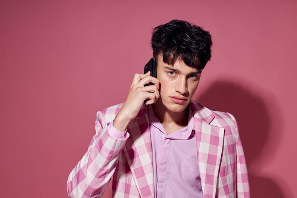 handsome guy with a phone in hand pink blazer fashion elegant style model studio - Zdjęcie, obraz