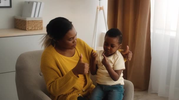 cuidando negro madre enseñando su pequeño hijo contando con dedos en casa - Metraje, vídeo