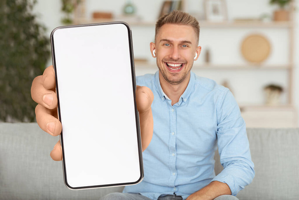 Κινητή διαφήμιση. Ενθουσιασμένος χαρούμενος άνθρωπος που δείχνει Smartphone με λευκή οθόνη - Φωτογραφία, εικόνα