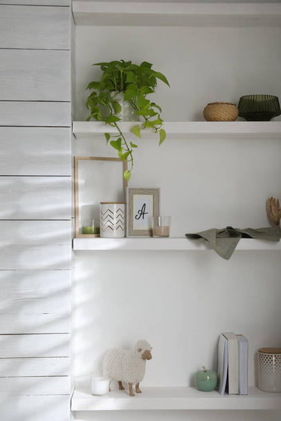 Wooden shelves with different decorative elements and houseplant on white wall - Fotografie, Obrázek