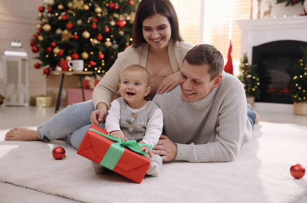 Happy family with cute baby on floor in room decorated for Christmas - Foto, imagen