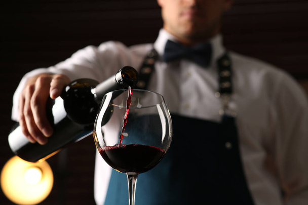 Bartender pouring red wine into glass indoors, closeup. Low angle view - Φωτογραφία, εικόνα