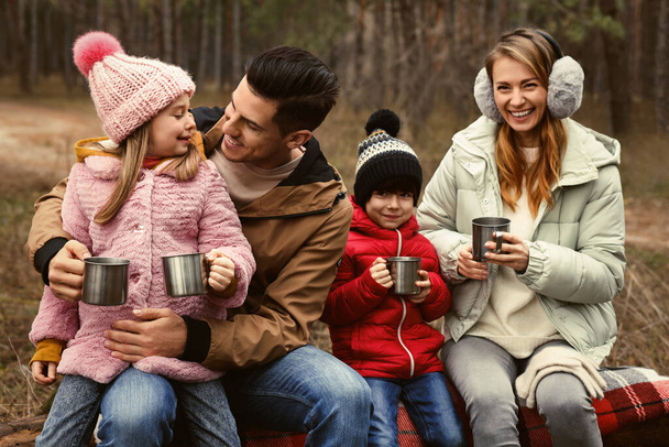 Happy family with hot drinks spending time together in forest - Fotoğraf, Görsel