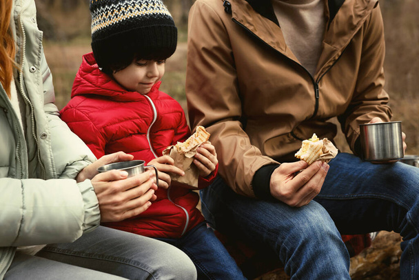 Happy family with sandwiches and hot drinks spending time together in forest, closeup - Photo, image
