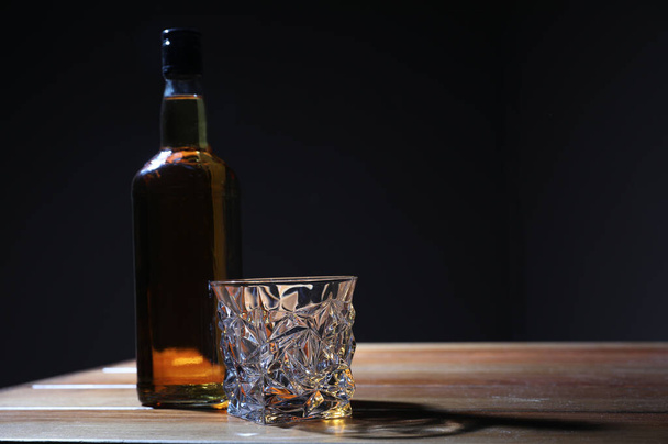 Whiskey on wooden table against dark background, space for text. Alcohol addiction - Фото, изображение