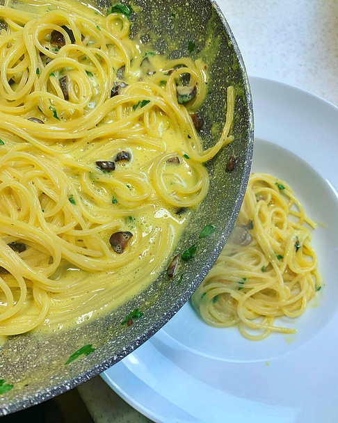 Italian pasta dish, spaghetti carbonara, creamy spaghetti with eggs, carbohydrates, warm pan, Italian specialties and classics - Fotó, kép