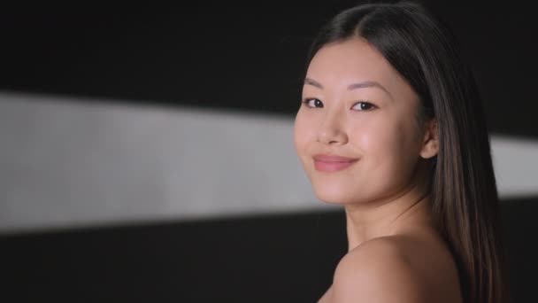 Moda y belleza. Estudio retrato de joven hermosa mujer asiática con hombros desnudos sonriendo a la cámara, espacio vacío - Imágenes, Vídeo
