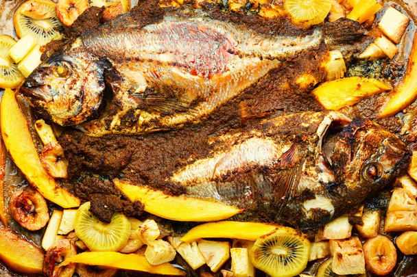 Delicious fried fish dorada with fruits and spices. - Fotó, kép