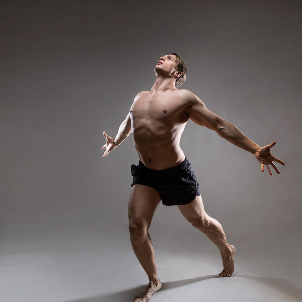 A young muscular man in an expressive pose. Beautiful muscles. - Zdjęcie, obraz