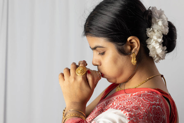 Красивая индийская женщина в красной сари дуть раковину на белом фоне - Фото, изображение
