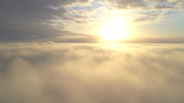 Vista aérea. Volando en la niebla, volar en la niebla sobre las nubes de la mañana temprano en el sol naciente. Cámara aérea grabada. Vuelo por encima de las nubes hacia el sol con las nubes de niebla flotando. Clima brumoso - Metraje, vídeo