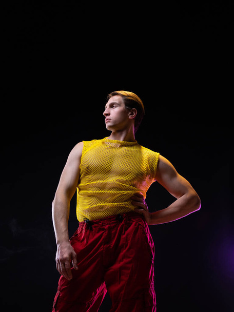 a young muscular man in a bright outfit poses in a pretentious pose, - Фото, зображення