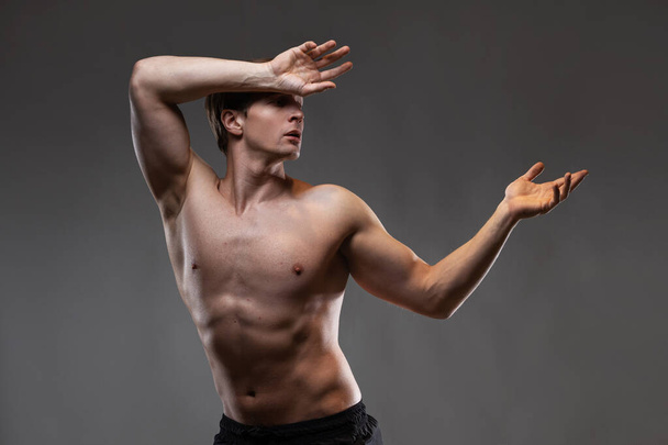 A young muscular man in an expressive pose. Beautiful muscles. - Foto, Bild