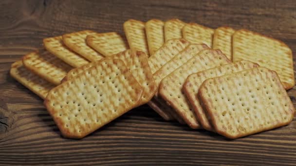 Dry salty cracker cookies isolated on wooden background - Filmati, video