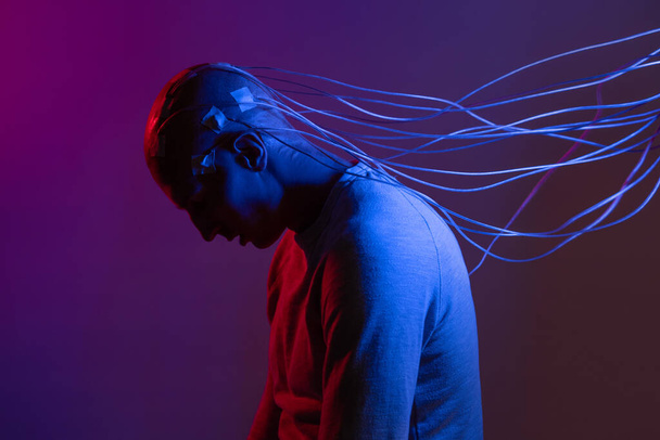 A young man with his head entangled with wires, a portrait in profile, - 写真・画像