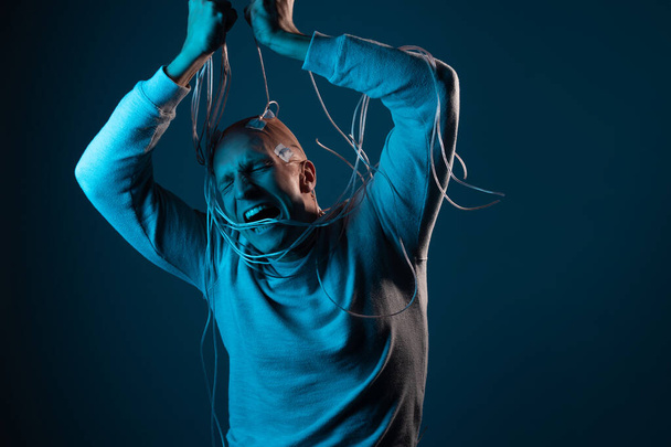 A young man with his head entangled in wires is trying to pull out contacts - Photo, image