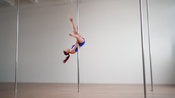Athletic vrouw paal danser voert acrobatische stunts met stretching elementen - Video