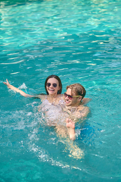 Young couple swimming in a pool and feeling excited - Foto, Bild