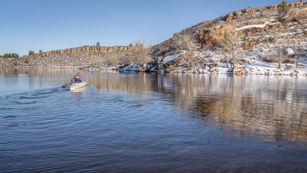 senior male wearing life jacket is paddling expedition canoe in winter scenery of Horsetooth Reservoir in northern Colorado - Фото, зображення