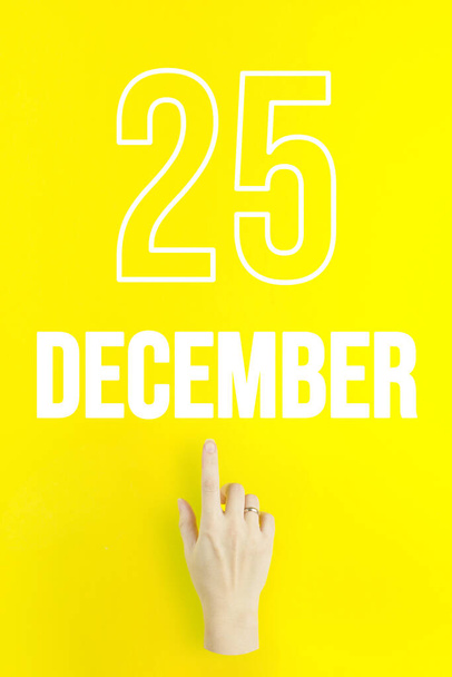 December 25th. Day 25 of month, Calendar date.Hand finger pointing at a calendar date on yellow background.Winter month, day of the year concept - Foto, afbeelding