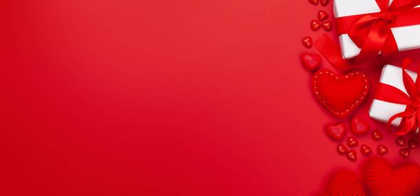 バレンタインデーグリーティングカードテンプレート。ギフトボックス、ハートの装飾、赤い背景にキャンディスイーツ。コピースペース付きのトップビューフラットレイ - 写真・画像