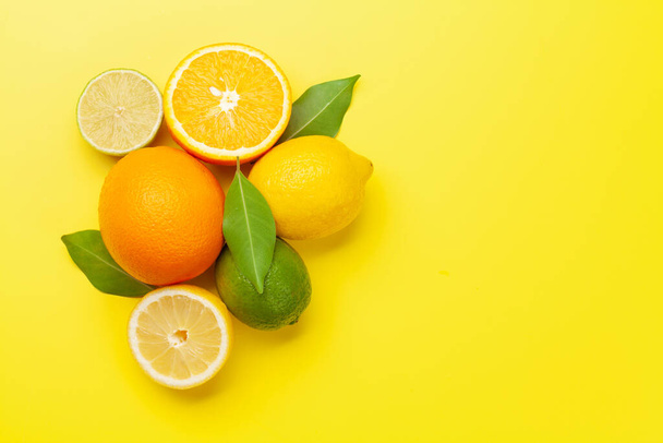黄色の背景に新鮮な熟した柑橘類。オレンジ、レモン、ライム。コピースペース付きのトップビューフラットレイ - 写真・画像
