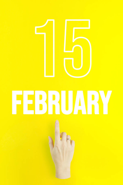 February 15th. Day 15 of month, Calendar date.Hand finger pointing at a calendar date on yellow background.Winter month, day of the year concept - Zdjęcie, obraz
