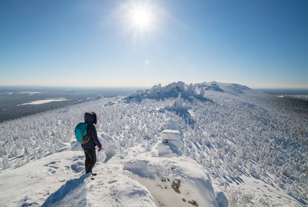 a tourist stands on top of a mountain in a snowy polar winter in sunny weather - Zdjęcie, obraz