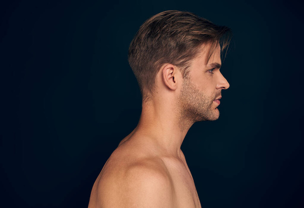 Handsome young man isolated. Portrait of shirtless muscular man is standing on dark blue background - Foto, Imagem