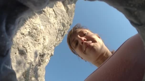 BOTTOM UP: Jonge vrouw krijt haar vingers tijdens het observeren van de klimroute. - Video