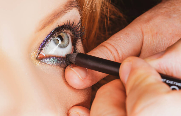 Make up eyes. Closeup of eye. Applying eyeligner, vadage, makeup. - Foto, afbeelding