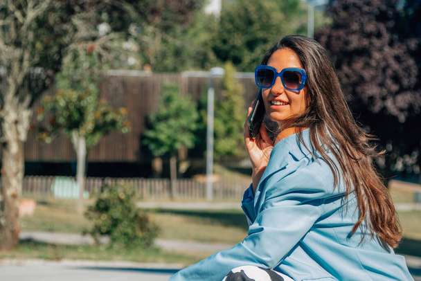 портрет дівчини з мобільним телефоном і сонцезахисними окулярами на відкритому повітрі
 - Фото, зображення