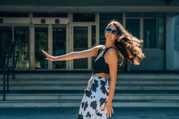 дівчина танцює на вулиці з волоссям на вітрі
 - Фото, зображення